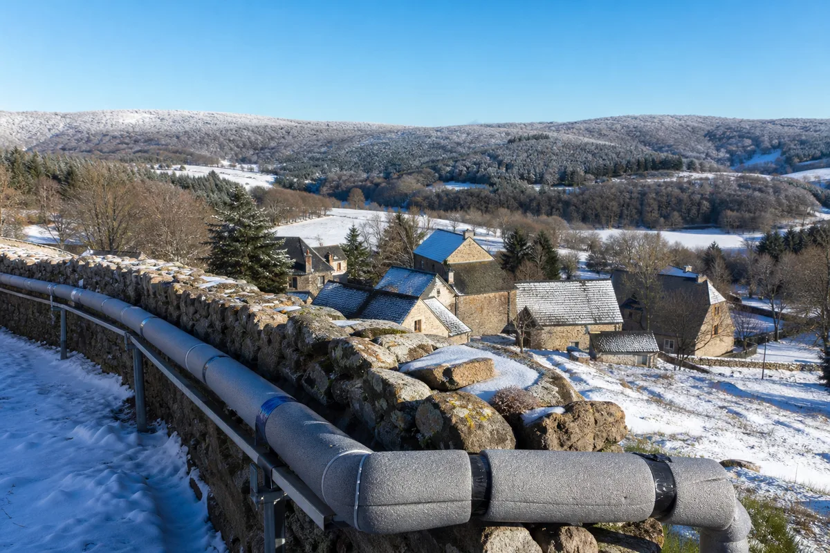 Vue des monts de Lacaune sous un ciel clair, hameau de montagne et canalisation extérieure protégée du gel